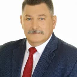 Portret mężczyzny w granatowej marynarce i czerwonym krawacie na białym tle.