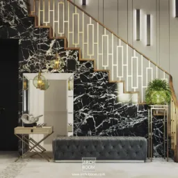 Eleganckie wnętrze z marmurową ścianą i schodami, oświetlone wiszącymi lampami i kinkietami, z ławką tapicerowaną i dekoracyjnym stolikiem przy lustrze.