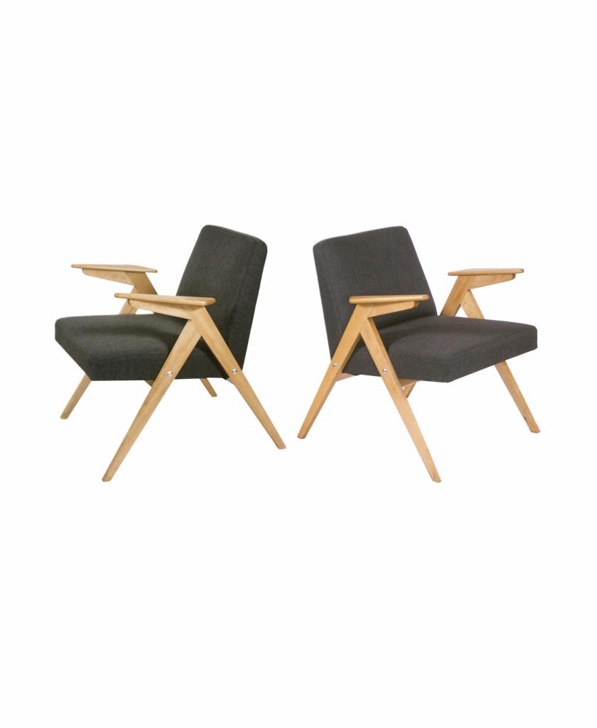 Dwa identyczne fotele z ciemnoszarą tapicerką i jasnymi drewnianymi nogami w stylu retro, ustawione symetrycznie na białym tle.