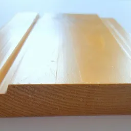 Profilowana deska z jasnego drewna, widoczny przekrój z wpustem i wypustem, gładka powierzchnia z wyraźnym usłojeniem, ułożona na białym tle.