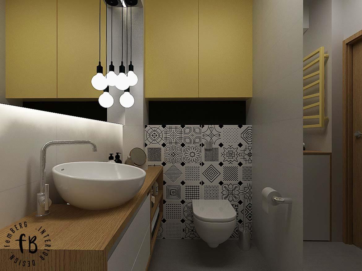 Nowoczesna łazienka z żółtymi szafkami, okrągłą umywalką nablatową, baterią w chromie, wzorzystymi płytkami nad toaletą i wiszącymi lampami z żarówkami Edison