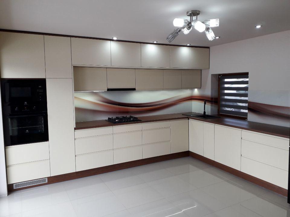 Jasna, nowoczesna kuchnia z brązowymi akcentami. Zabudowa z piekarnikiem, płyta grzewcza, okap i szafki. Brązowy blat i panel nad blatem z motywem fal.