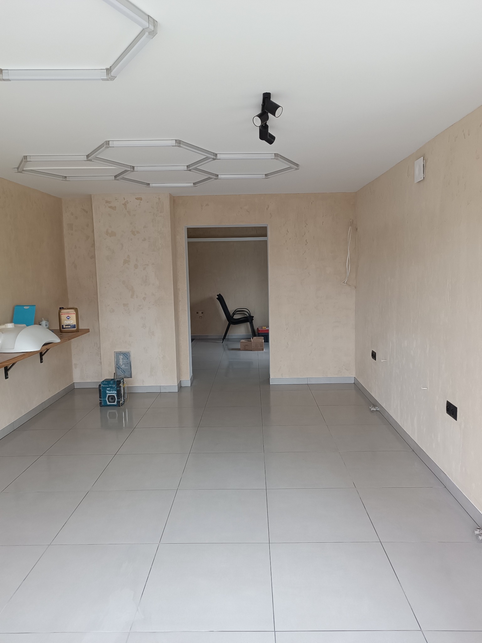 Wykończone wnętrze po remoncie w Witnicy: jasne ściany z fakturą, szare płytki podłogowe, nowoczesne oświetlenie sufitowe. Widoczne narzędzia i materiały budowlane.