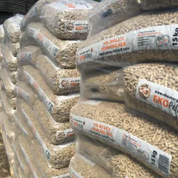 Stos worków z pelletem drzewnym EKO Pellets, ułożonych na palecie, widoczne etykiety z informacjami o produkcie i wadze 15 kg.