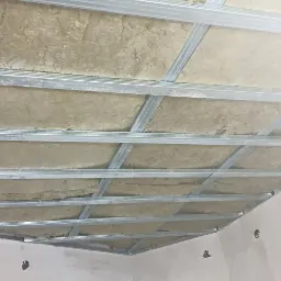 Sufit podwieszany z metalową konstrukcją i ociepleniem z wełny mineralnej, widoczne otwory w ścianie