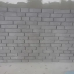 Świeżo ułożona szara ściana z cegieł z widocznymi śladami zaprawy na górze.