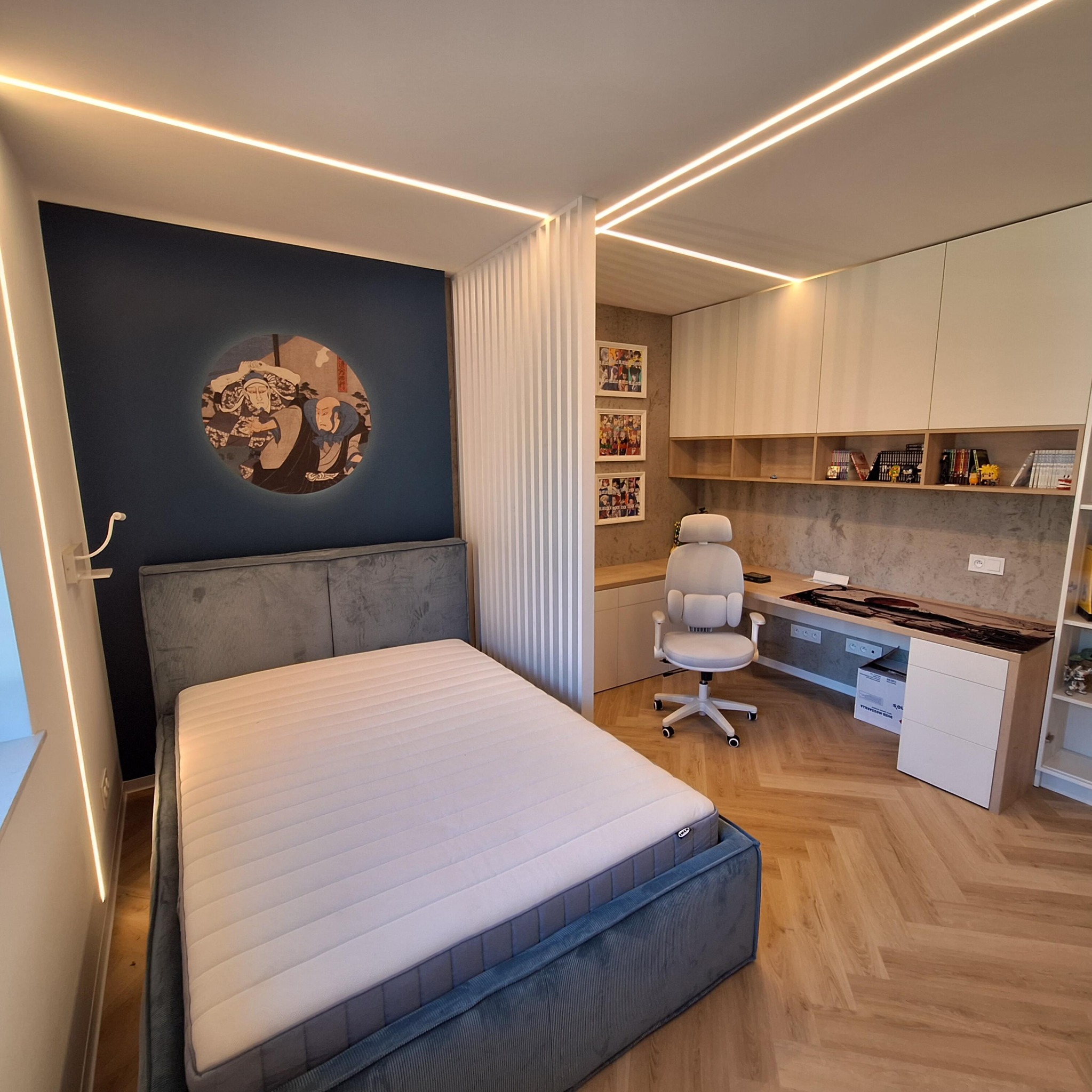Nowoczesna aranżacja pokoju z łóżkiem, biurkiem i oświetleniem LED. Parkiet w jodełkę, niebieska ściana z grafiką i białe meble tworzą spójną całość.