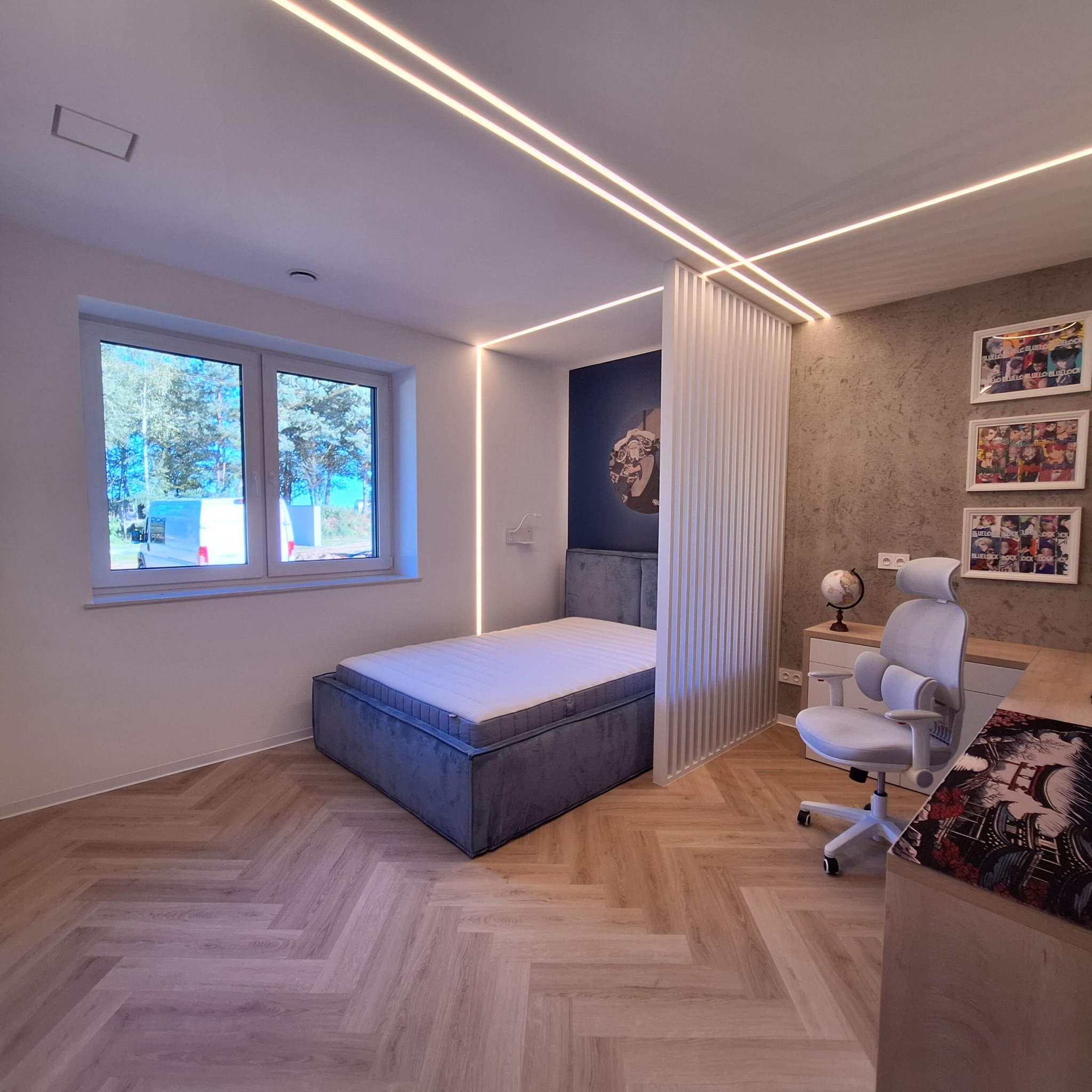 Nowoczesna sypialnia z łóżkiem, biurkiem i oświetleniem LED. Parkiet ułożony w jodełkę. Ściana z dekoracyjną tapetą i obrazami. Białe meble i krzesło.