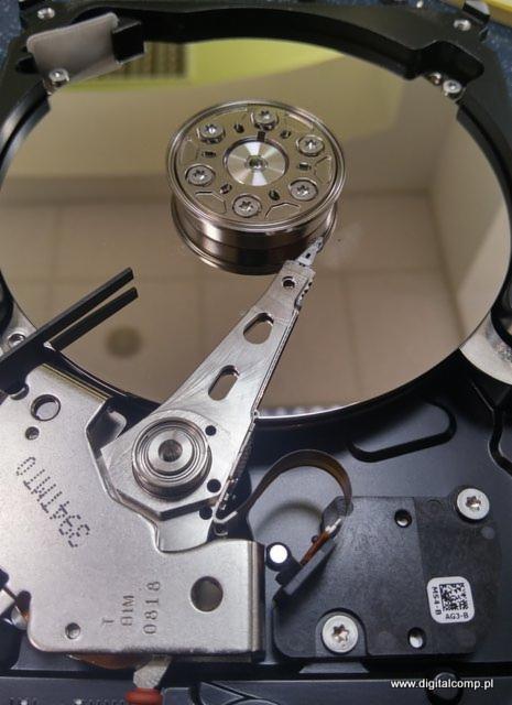 Wnętrze dysku twardego z widoczną głowicą i talerzem, z bliska, ukazujące precyzyjną mechanikę.