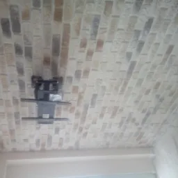 Sufit wykończony tapetą imitującą cegłę z zamontowanym uchwytem do telewizora