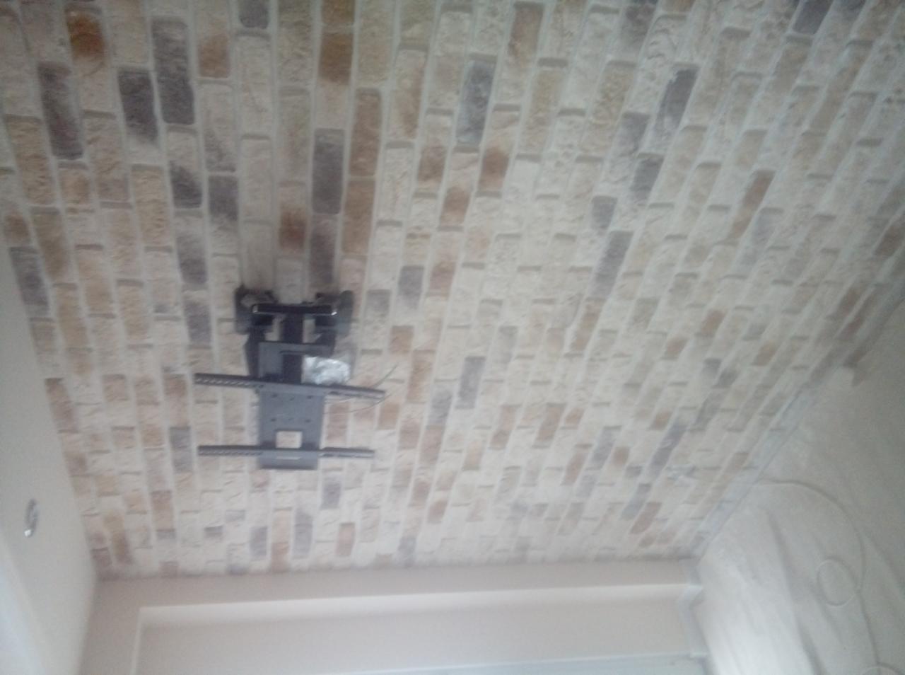 Sufit wykończony tapetą imitującą cegłę z zamontowanym uchwytem do telewizora