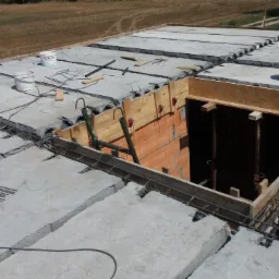 Betonowy strop Teriva w trakcie budowy z widocznymi pustakami, zbrojeniem, deskowaniem otworu i wiaderkami po farbie.