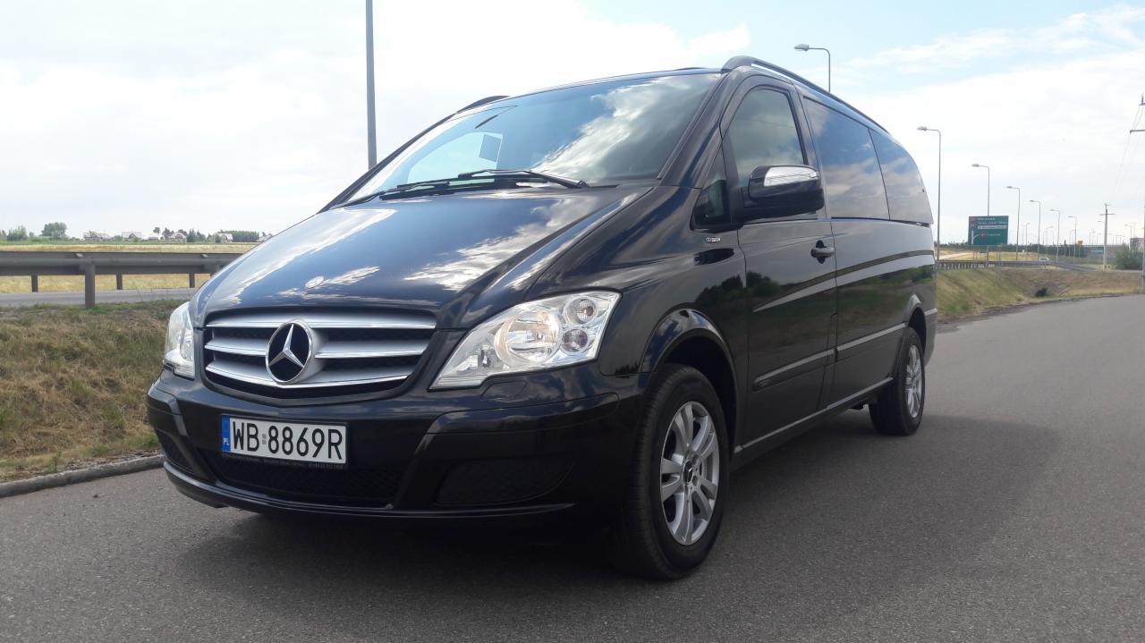 Czarny Mercedes Vito z polskimi tablicami rejestracyjnymi WB 8869R, zaparkowany na asfalcie przy drodze, widok z przodu i z boku.