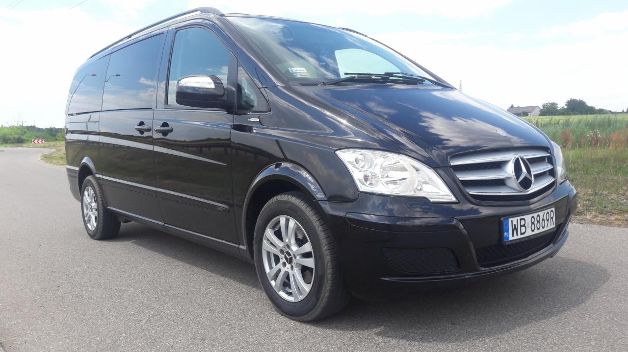 Czarny, lśniący van Mercedes-Benz Viano na asfaltowej drodze, widoczny znak drogowy w tle.