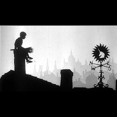 Sylwetka kominiarza siedzącego na kominie z narzędziami, na tle panoramy miasta i wiatrowskazu w kształcie zająca.