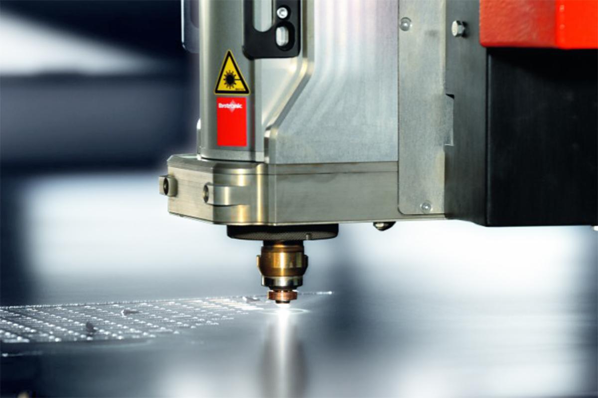 Precyzyjna obróbka metalu: detale głowicy lasera CNC podczas cięcia blachy, widoczne iskry i drobne otwory w materiale.