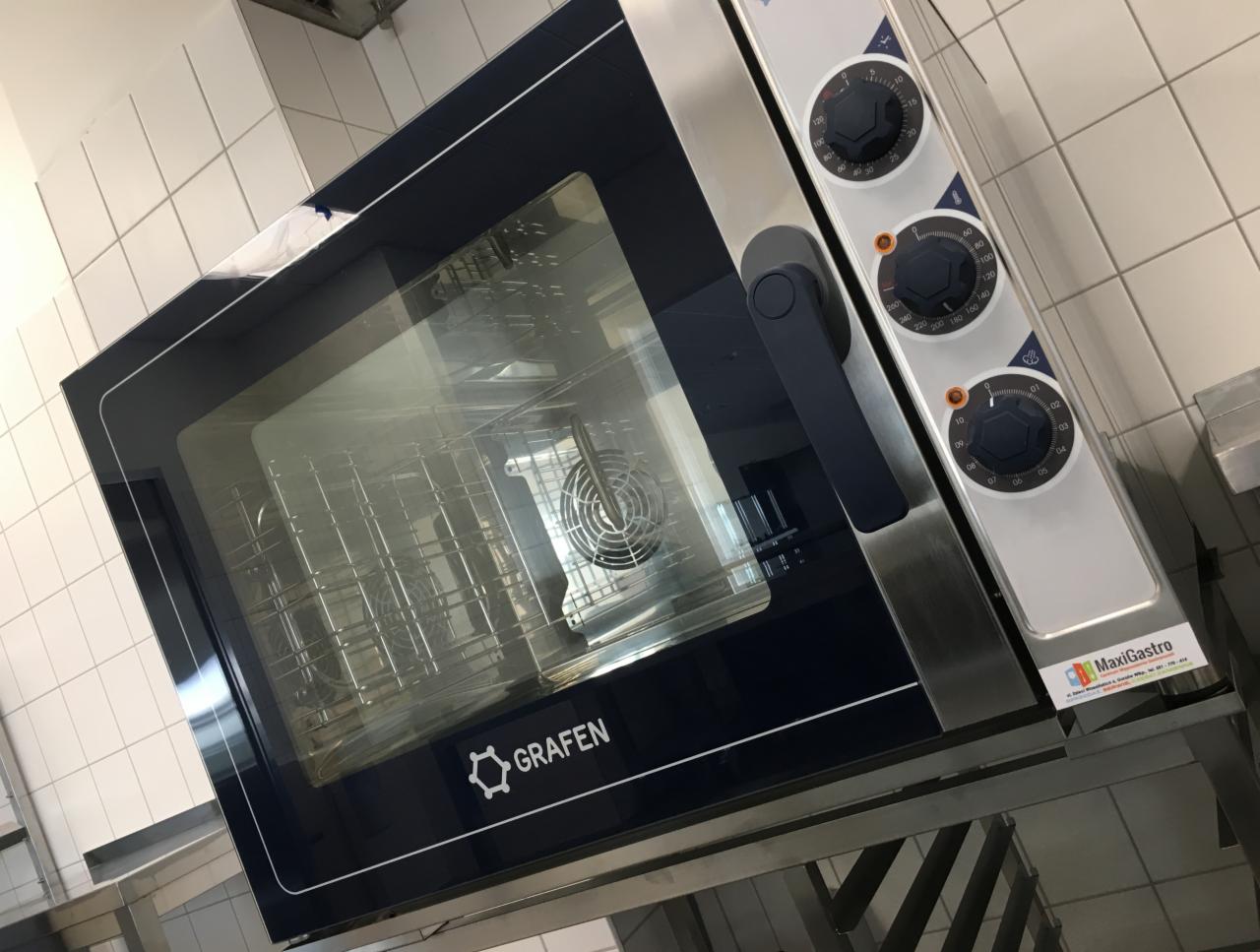 Profesjonalny piekarnik konwekcyjny Grafen z widocznym wentylatorem i trzema pokrętłami sterującymi, umieszczony w lokalu z białymi kafelkami na ścianach.