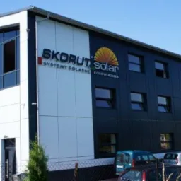 Nowoczesny budynek biurowy firmy Skórut Solar z dużymi oknami i logo firmy na elewacji, systemy solarne fotowoltaika.