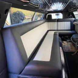 Wnętrze luksusowej limuzyny z odnowioną tapicerką w kolorze czarno-białym, z błyszczącym, lustrzanym sufitem i widocznymi elementami wykończeniowymi.