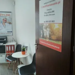 Wnętrze biura kredytowego z plakatem 'Pożyczki Pozabankowe', stolikiem z rośliną, oraz ogłoszeniem agencji kredytowej z ofertą kredytów i pożyczek, w tym pożyczek bez BIK.