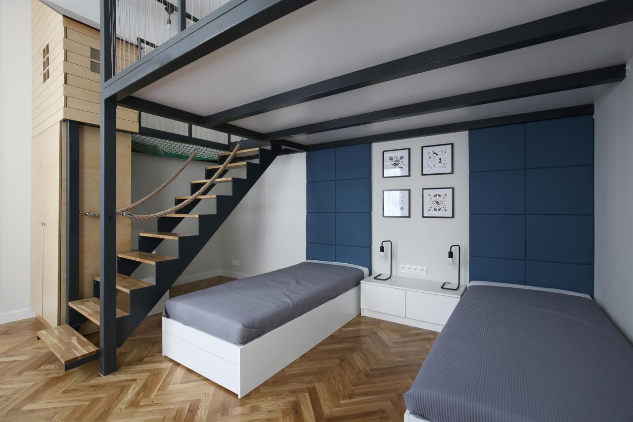 Pokój dziecięcy z dwoma łóżkami, antresolą z drewnianą drabinką linową, zabudową meblową z domkiem na górze i panelami ściennymi w kolorze granatowym.