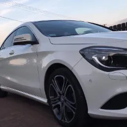 Biały samochód osobowy marki Mercedes po umyciu, zaparkowany na kostce brukowej w Koniuszy, widok z boku, czyste felgi.