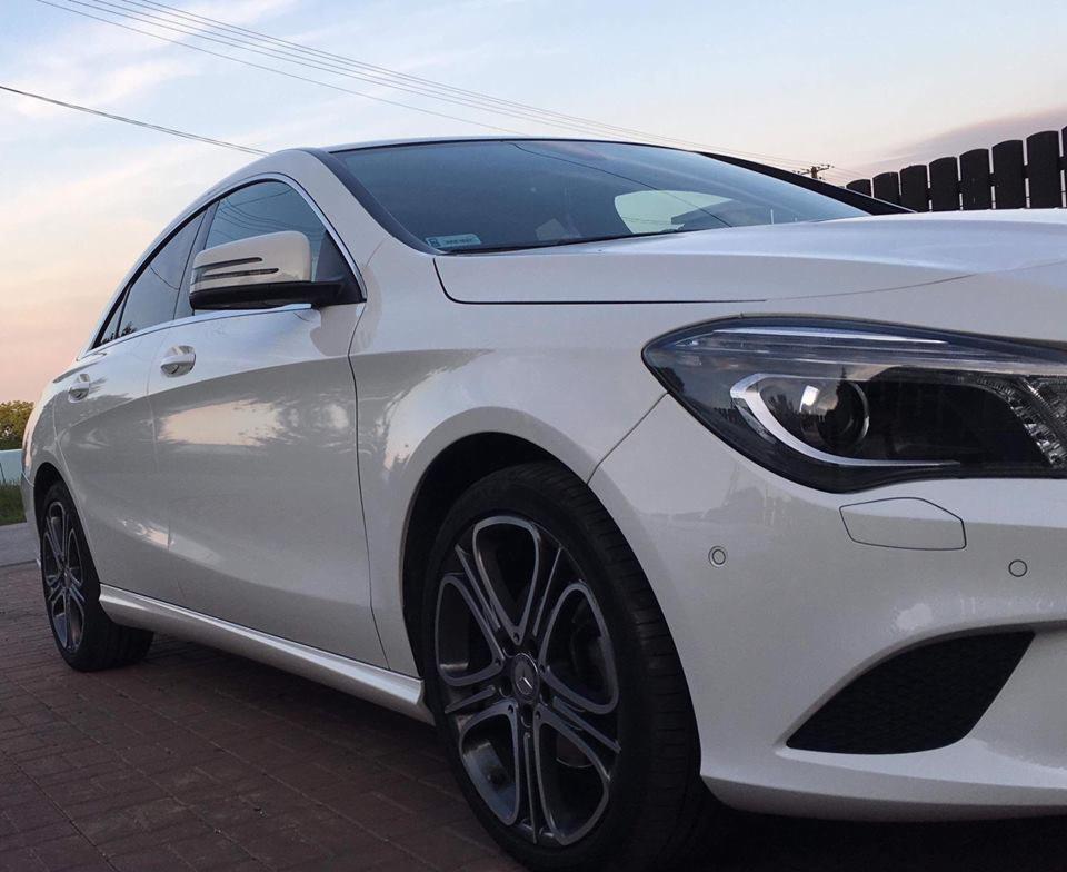 Biały samochód osobowy marki Mercedes po umyciu, zaparkowany na kostce brukowej w Koniuszy, widok z boku, czyste felgi.