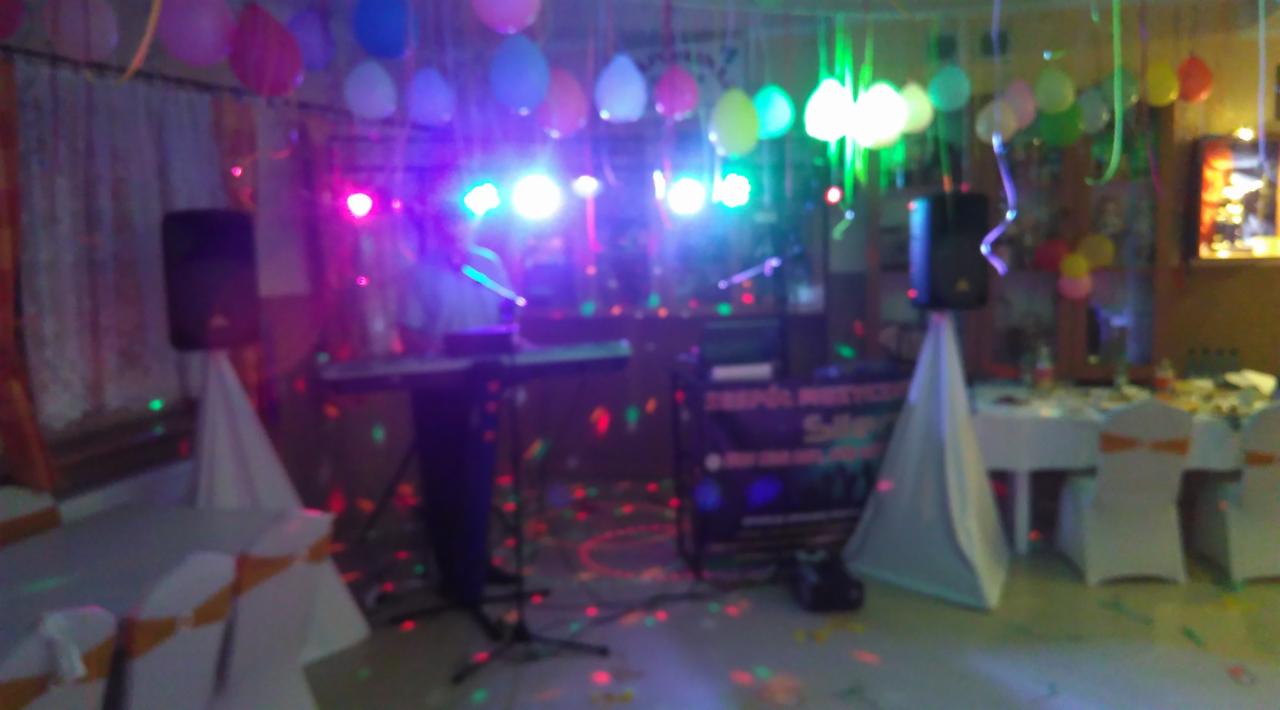 Scena z instrumentami, nagłośnieniem i kolorowymi światłami, przygotowana na imprezę z dekoracjami balonowymi.