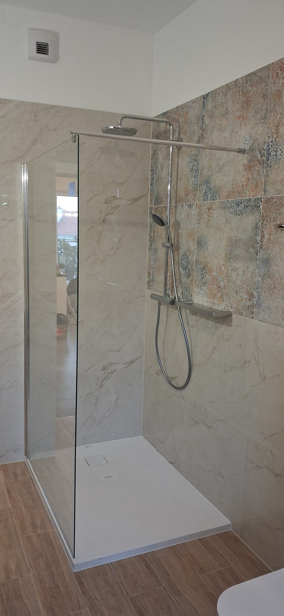 Nowoczesna kabina prysznicowa walk-in z deszczownicą i płytkami imitującymi marmur oraz dekoracyjnymi. Widoczny odpływ liniowy i szklana ścianka.