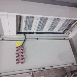 Otwarta szafa elektryczna z panelami rozdzielczymi i okablowaniem wentylatorów chłodzących na wewnętrznej stronie drzwi.