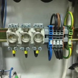 Szczegółowe ujęcie z bliska podłączonych przewodów w rozdzielnicy elektrycznej, widoczne złącza śrubowe, oznaczenia N, L1, L2, L3, PE oraz przewody o różnych kolorach.