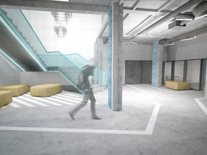 Surowy betonowy hol biurowy z turkusową metalową klatką schodową, żółtymi pufami i rozmytą sylwetką przechodzącej osoby.