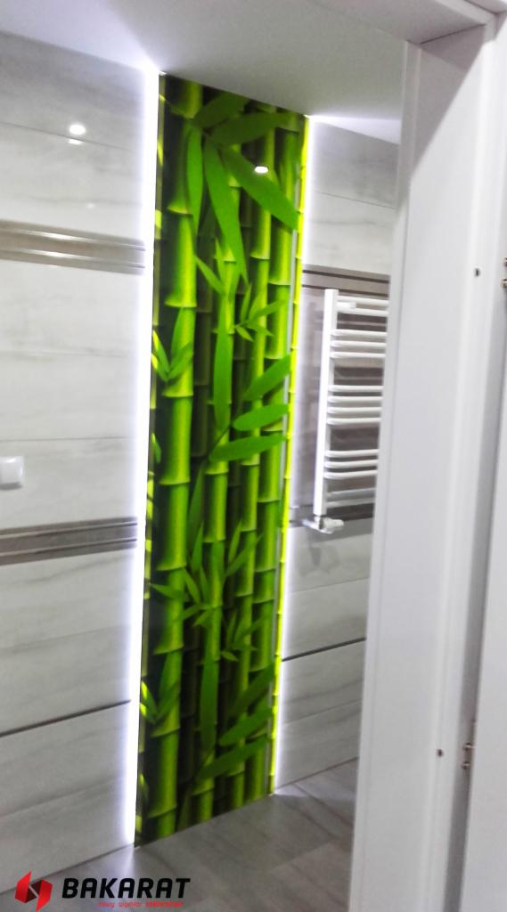 Panel szklany z motywem bambusa, podświetlony LED, wkomponowany w ścianę łazienki z jasnymi płytkami.