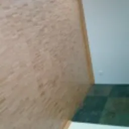 Fragment parkietu na ścianie i podłodze, widoczne przejście między powierzchniami, jasne drewno, ciemne kwadraty na podłodze.