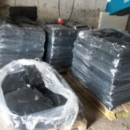 Stosy workowanego opału w czarnych foliach, ułożone na paletach w magazynie, widoczne z bliska, z datą na dole zdjęcia.