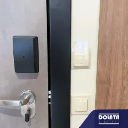 Drzwi z zamkiem elektronicznym na kartę, obok włącznik światła i czytnik kart, nowoczesne rozwiązanie kontroli dostępu.