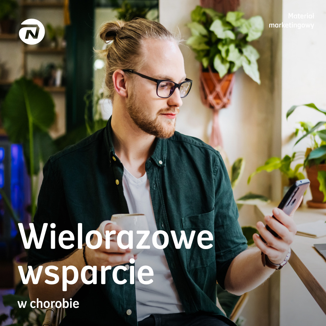 Młody mężczyzna w okularach trzymający smartfon i filiżankę, siedzący w jasnym wnętrzu z roślinami, tekst 'Wielorazowe wsparcie w chorobie' na pierwszym planie.