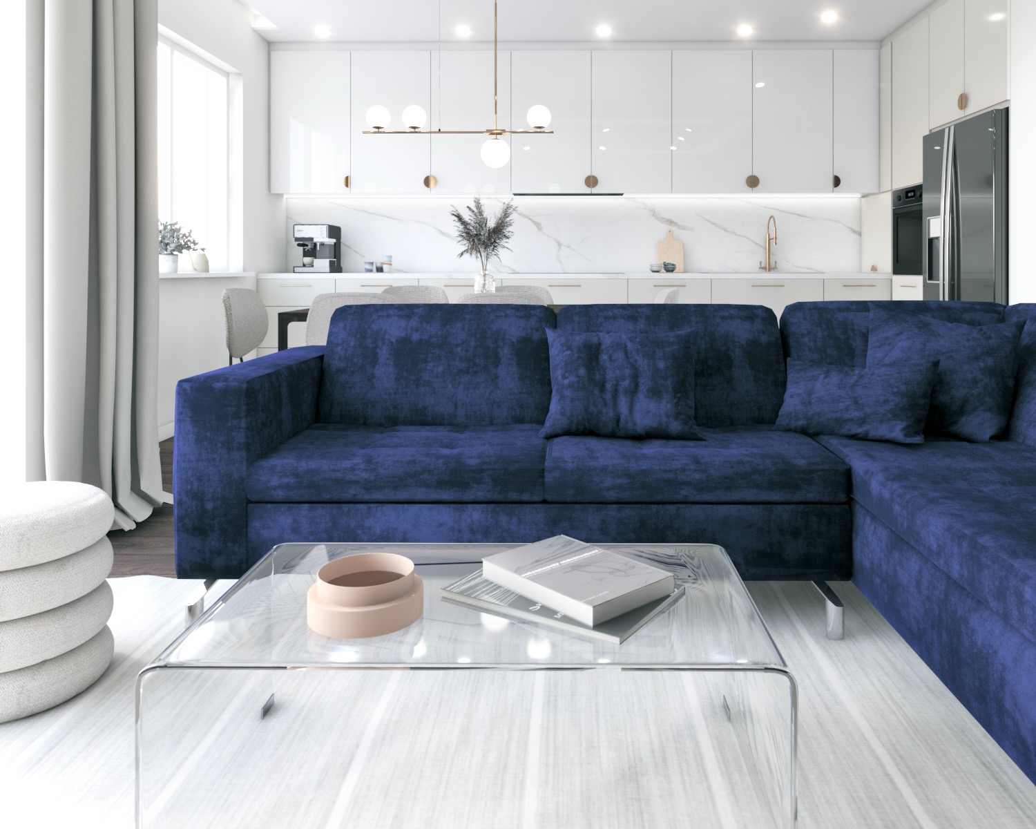 Nowoczesny salon z granatową sofą z aksamitu, szklanym stolikiem kawowym i otwartą kuchnią w bieli, oświetloną złotą lampą wiszącą.