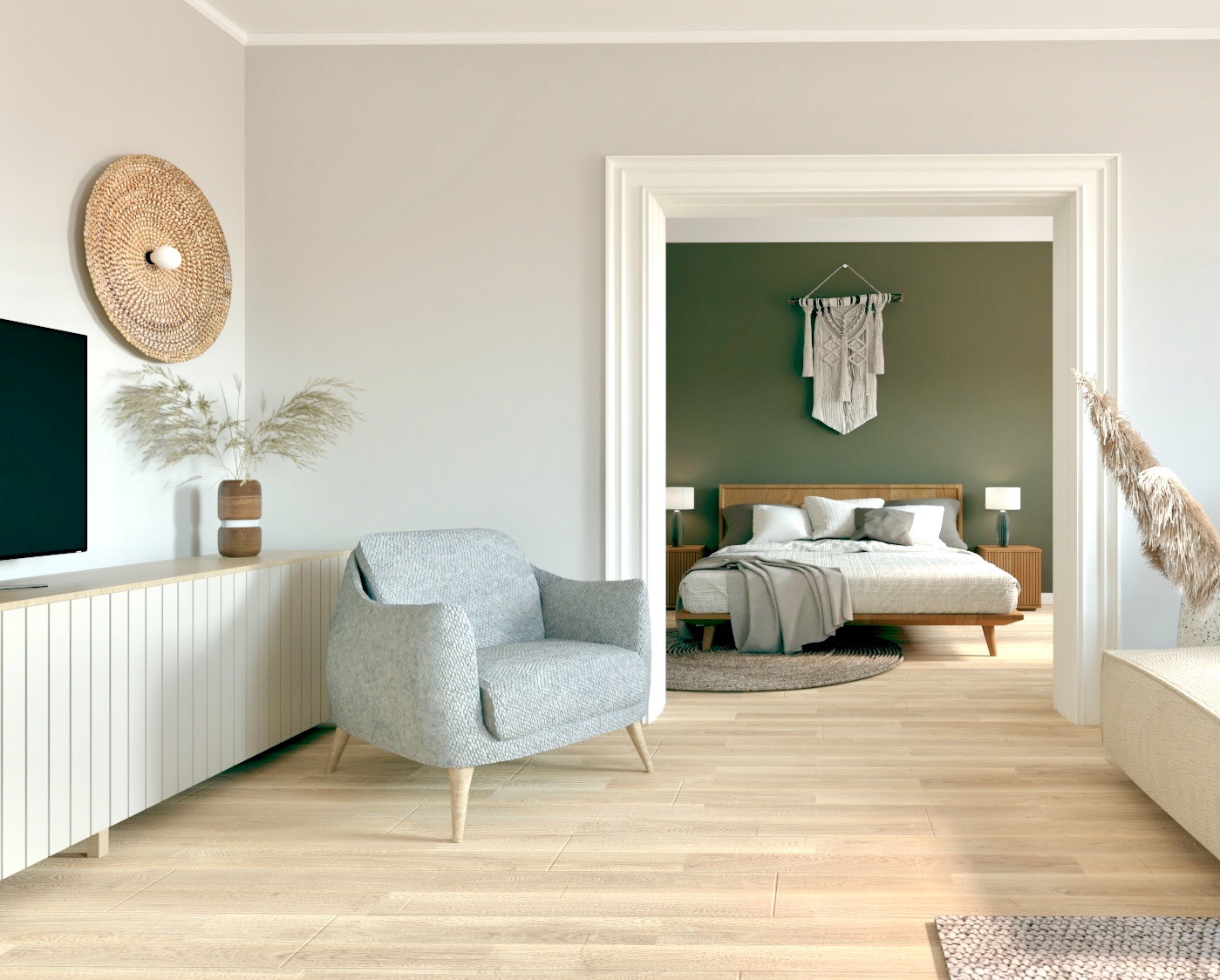 Jasny salon z szarym fotelem na tle telewizora, komody i dekoracji ściennej z rafii; w głębi widoczna sypialnia w stylu boho z makramą na zielonej ścianie.