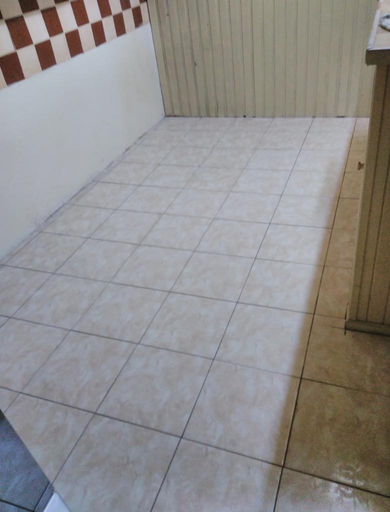 Płytki podłogowe w pomieszczeniu z częściowo wykończonymi ścianami, widoczne brązowo-białe płytki na ścianie i drewniane panele.