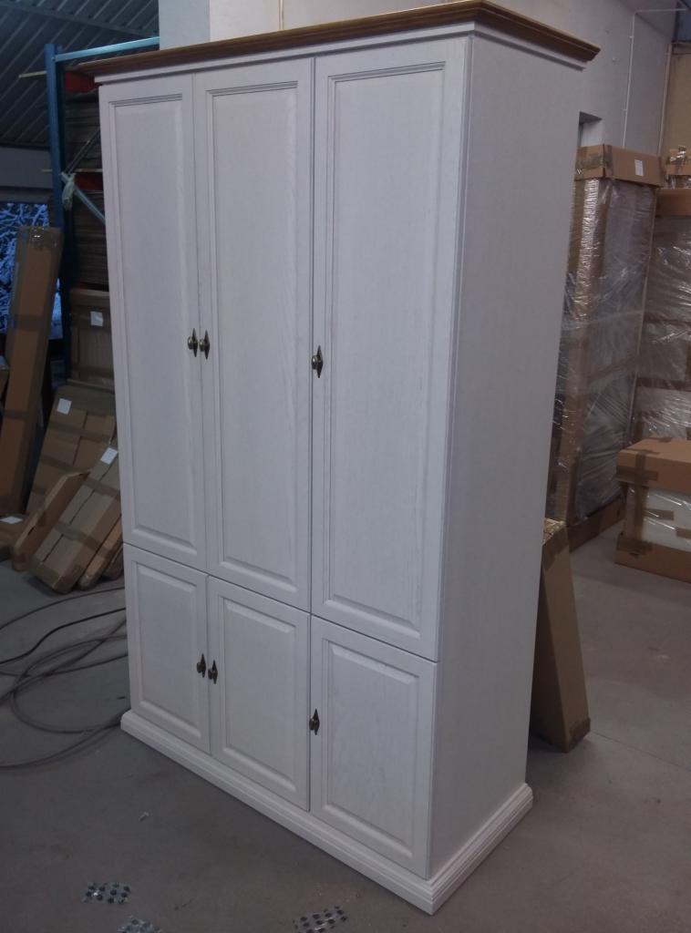 Biała szafa trzydrzwiowa z drewnianym blatem w magazynie, widoczne kartony w tle.