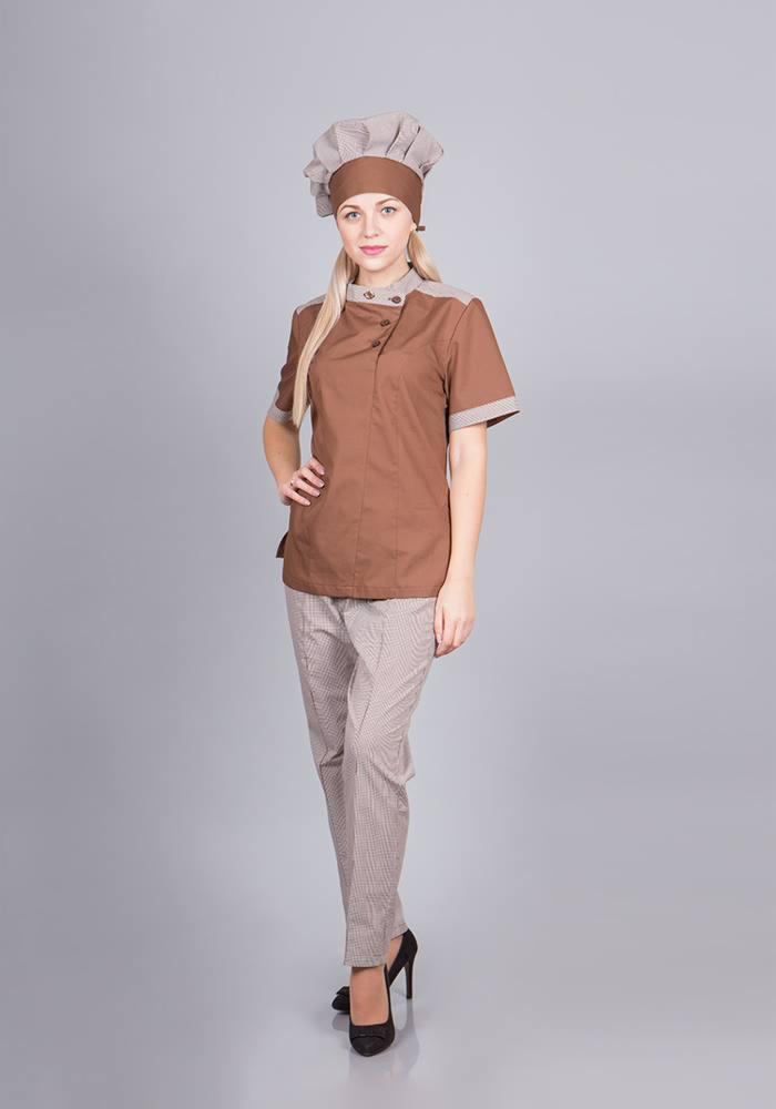 Kobieta w brązowym uniformie kucharskim z czapką i spodniami w drobną kratę, pozuje na szarym tle, prezentując strój roboczy.