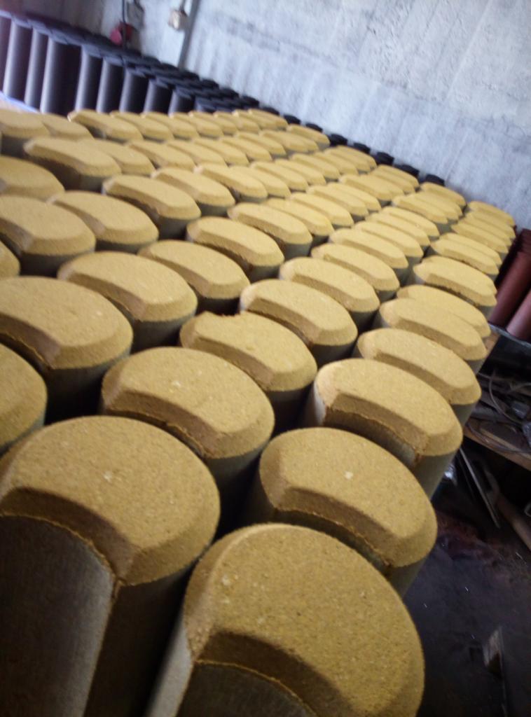 Magazyn w Lipnie wypełniony rzędami betonowych elementów o zaokrąglonym kształcie, prawdopodobnie kostki brukowej lub obrzeży, ustawionych pionowo na paletach.