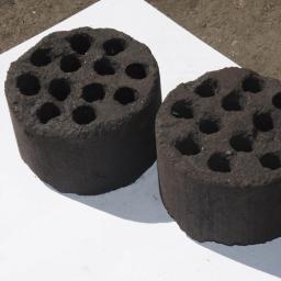 Eko Patent Sp. z o.o. - Dwa cylindryczne brykiety z otworami, ułożone na białym papierze na szarym, betonowym podłożu.
