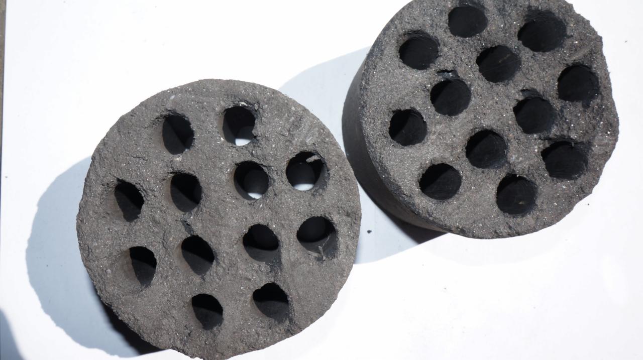 Dwa okrągłe brykiety z otworami na białym tle, ukazujące ich teksturę i budowę.