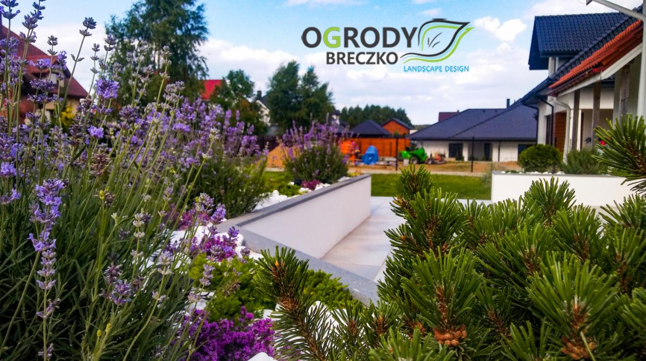 Nowoczesny ogród z niską, białą donicą wypełnioną białym żwirem i fioletową lawendą, z widocznym logo firmy na górze zdjęcia.