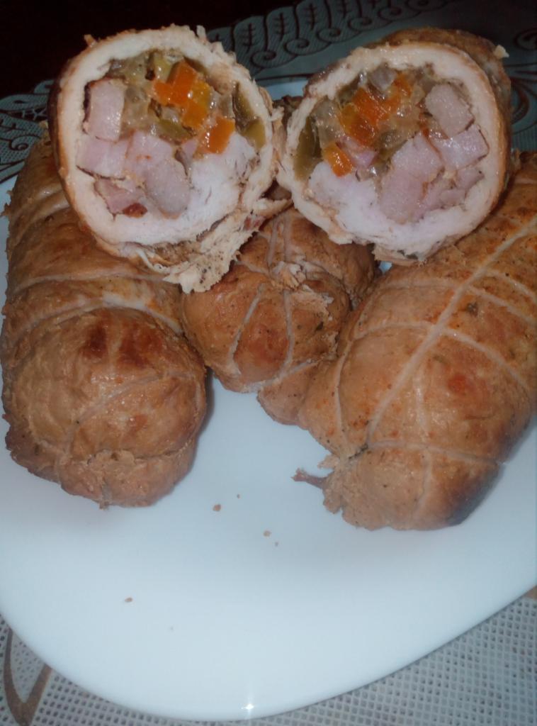 Rolada mięsna z nadzieniem warzywnym, przekrojona na pół, leżąca na białym talerzu. Widoczne kawałki mięsa, marchewki i ogórka w środku. Całość związana sznurkiem.