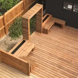 Nowoczesny taras z drewna z wbudowanymi donicami i drewnianą konstrukcją wejściową, widok z góry.