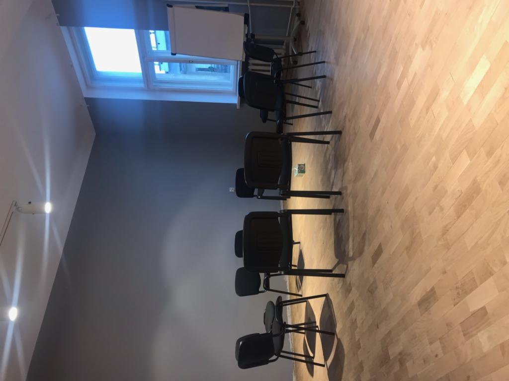 Pusta sala konferencyjna z rzędem krzeseł ustawionych przed tablicą flipchart pod oknem dachowym, widok z boku.