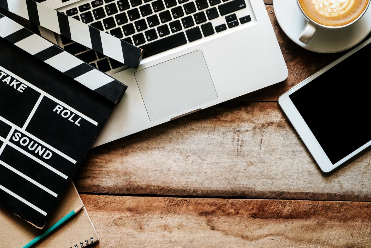 Klapka filmowa, laptop, tablet i kawa na drewnianym stole. Koncepcja tworzenia treści wideo.